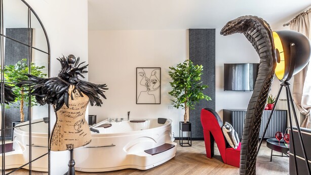 Un salon moderne avec une grande baignoire blanche, un fauteuil rouge et une sculpture originale.