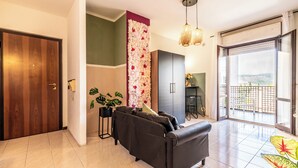 A modern living room with a sofa, a decorative wall, and a view through a large window. - Luxury Suite - Tentazioni Romantiche (Perugia)