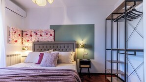 A bedroom with a bed, a nightstand, a wall-mounted shelf, and a hanging clothes rack. - Luxury Suite - Tentazioni Romantiche (Perugia)