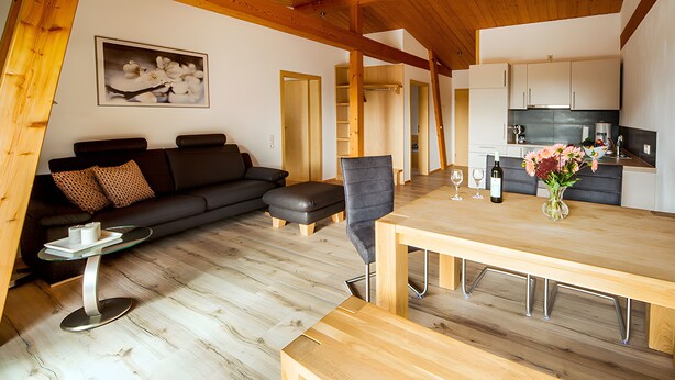 Un espace de vie moderne doté d’un plancher en bois, d’un canapé, d’une table à manger et d’un coin cuisine.