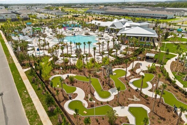 Un resort con piscina central, áreas ajardinadas y varias construcciones.