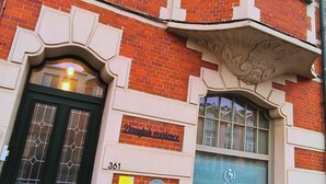 Een gebouw van rode bakstenen, met een zwarte deur, een bordje waarop '2e verdieping appartement' staat en het getal '361' onder de deur.