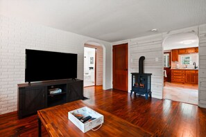 Un salon équipé d’un téléviseur à écran plat, d’un meuble de rangement en bois foncé et d’une table basse avec une télécommande.