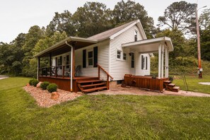 Een gelijkvloers huis met veranda, houten trap en een klein terras.