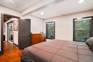 A bedroom with a bed, dresser, and two windows with blinds. - On The Rocks | Hocking Hills, 4BR, Hot Tub (South Bloomingville)