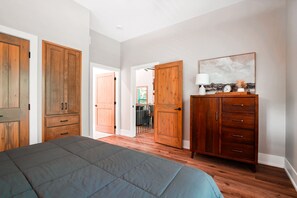 A bedroom with a bed, wooden wardrobe, and a painting on the wall. - On The Rocks | Hocking Hills, 4BR, Hot Tub (South Bloomingville)