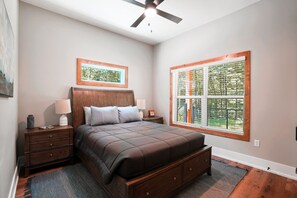 A bedroom with a bed, nightstands, a ceiling fan, a window with blinds, and a framed picture on the wall. - On The Rocks | Hocking Hills, 4BR, Hot Tub (South Bloomingville)