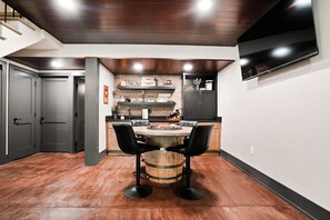 Une cuisine moderne avec un îlot central en bois, des tabourets de bar noirs et un téléviseur encastré.