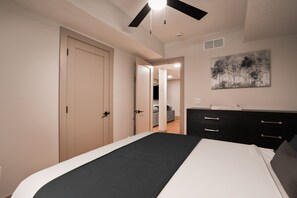 A bedroom with a bed, a dresser, a door, and a painting on the wall.