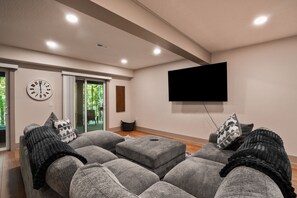 A modern living room with a sofa set, a flat-screen TV, and a clock on the wall.