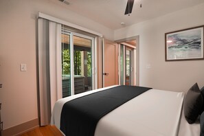 A bedroom with a bed, a door leading to a balcony, and a framed picture on the wall. - Onyx Ridge | Hocking Hills, Luxury Cabin, Hot Tub (South Bloomingville)