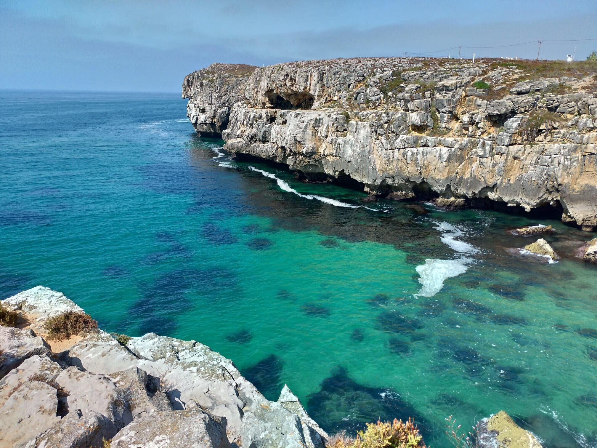 Een kustlandschap met rotskliffen en helder turquoise water.