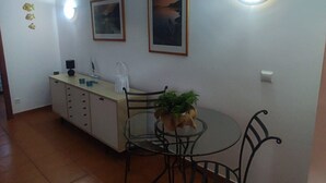 A small kitchen with a dining table and chairs, a cabinet, and two framed pictures on the wall. - Peniche Nature and Beach Flat (Peniche)