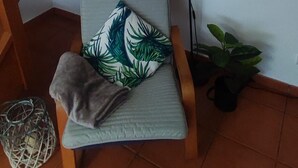A cozy corner with a cushioned chair, a hanging sign, a lamp, and a potted plant. - Peniche Nature and Beach Flat (Peniche)