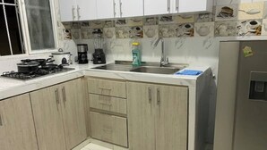 A kitchen with white cabinets, a stove, a sink, and a refrigerator. - Spacious apartment in Palmira, peace (Palmira)