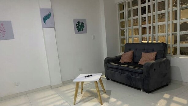 A room with a grey sofa, a small white table, and artwork on the walls. - Spacious apartment in Palmira, peace (Palmira)