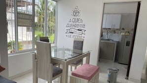 A dining area with a glass table and chairs, a kitchen in the background, and a wall with a coffee-themed sign. - Spacious apartment in Palmira, peace (Palmira)