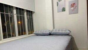 A bed with a quilted grey bedspread and two pillows with a white grid pattern. - Spacious apartment in Palmira, peace (Palmira)