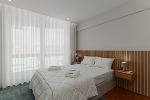 A hotel room with a large bed, a nightstand with a lamp, and sheer curtains. - Apartment 'O Navegador' with Balcony, Wi-Fi and Air Conditioning (Porto)