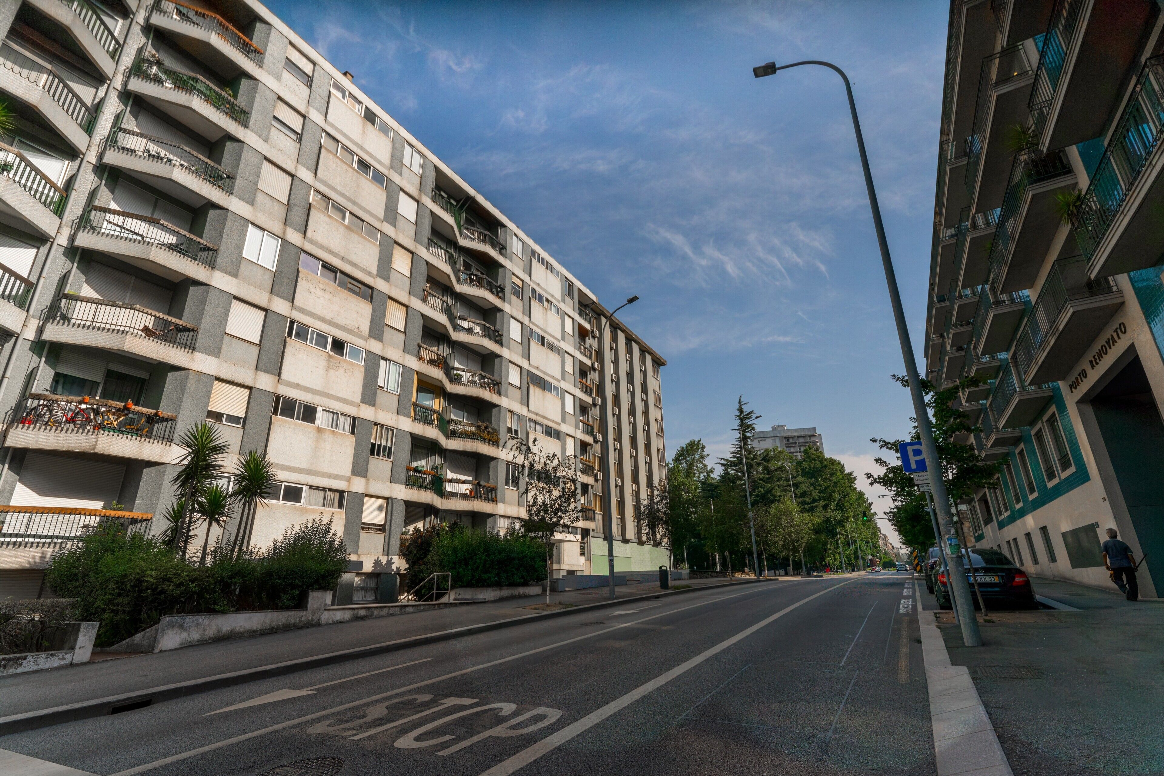A multi-story building with balconies, a clear sky, and a road with a stop line.
