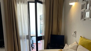 Ein Hotelzimmer mit einem Bett, einem Fernseher, einer Wandleuchte und Blick ins Freie.