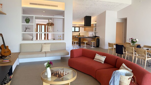 A modern living room with a sofa, a glass coffee table, and a bookshelf.
