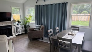 A cozy living room with a fireplace, a television, and a dining area with a table and chairs.