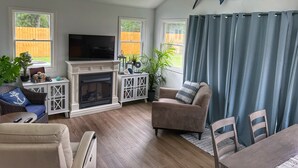 A living room with a fireplace, television, and a ceiling fan.