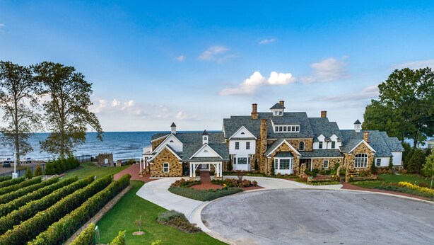 A large, multi-story house with a stone facade, a spacious driveway, and a well-maintained lawn.