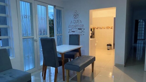 A dining area with a table and chairs, a bench, and a wall with a decorative sign. - Comfortable apartment in Palmira, fe (Palmira)