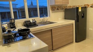A modern kitchen with a gas stove, sink, and black refrigerator. - Comfortable apartment in Palmira, fe (Palmira)