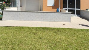 Un edificio residencial de dos pisos con balcón, garaje y un pequeño patio.