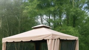 Un espace extérieur abrité, aménagé avec une table et des chaises, entouré d’une terrasse en bois et d’une rambarde.