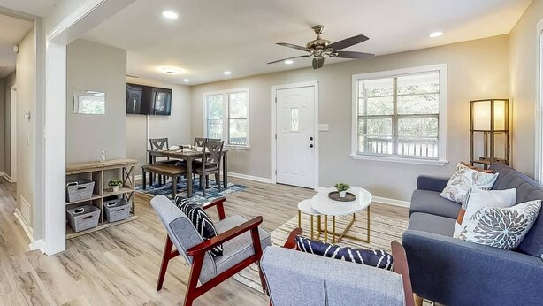 A spacious living room with a ceiling fan, a sofa, a coffee table, and a dining area with chairs and a table.