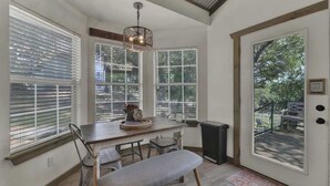 A dining area with a wooden table, chairs, a bench, and a chandelier. - Cactus Flower Lodge-20 min to Downtown-starlit Sky Views (Fredericksburg)