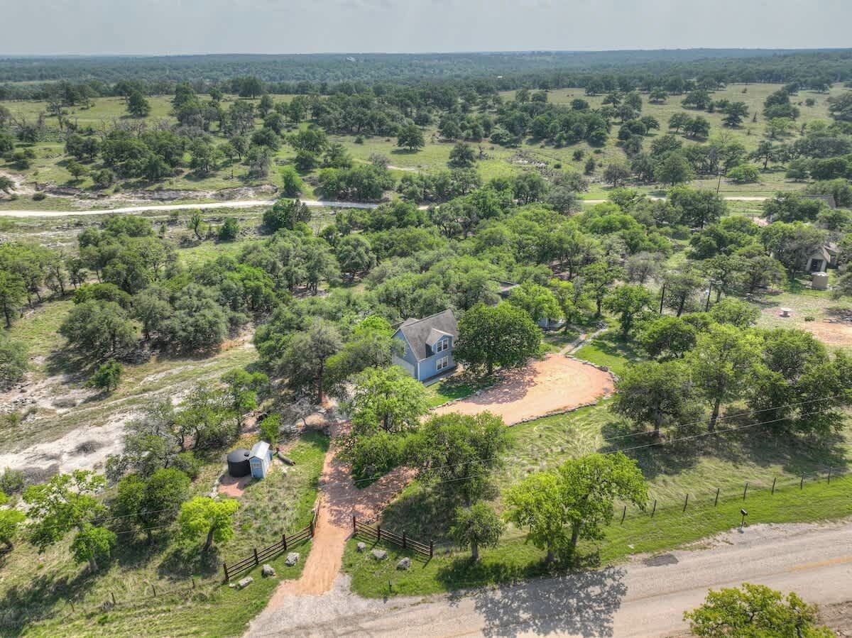 A rural property with a house surrounded by trees and open fields.