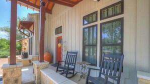 A covered porch with stone steps, two rocking chairs, and a small table. - Casa Blanca-swim Spa-steps to Main Street! (Fredericksburg)