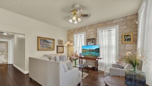 Ein Wohnzimmer mit einem weißen Sofa, einem Fernseher und einer Steinwand.