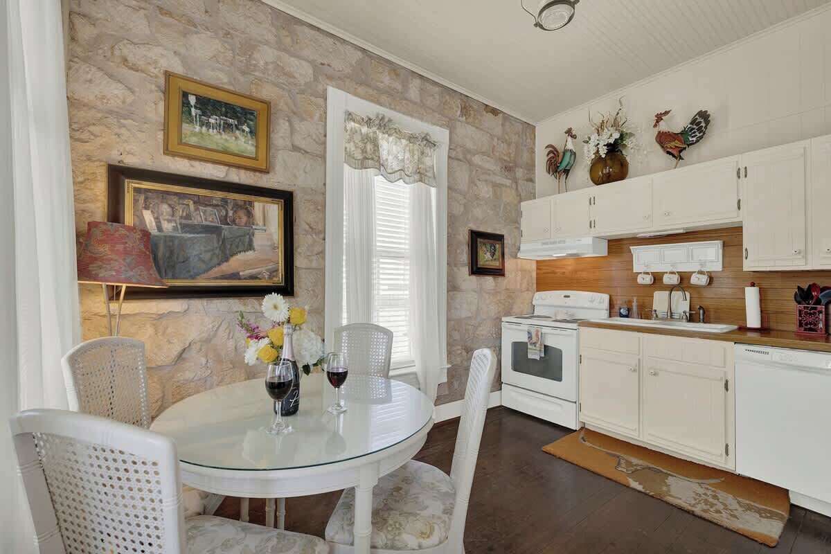 A kitchen with white cabinets, a dining table with chairs, a stove, and decorative wall art.