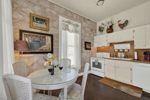 Una cocina con armarios blancos, una mesa de comedor con sillas, una estufa y decoración en las paredes.