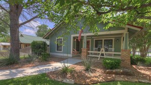 A house with a porch, a flag, and a tree. - Charming Cottage-3 Mins to Downtown-pet Friendly! (Fredericksburg)