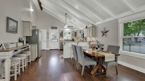 A spacious kitchen with a central island, white cabinetry, and a dining area with a wooden table and chairs. - Charming Cottage-3 Mins to Downtown-pet Friendly! (Fredericksburg)