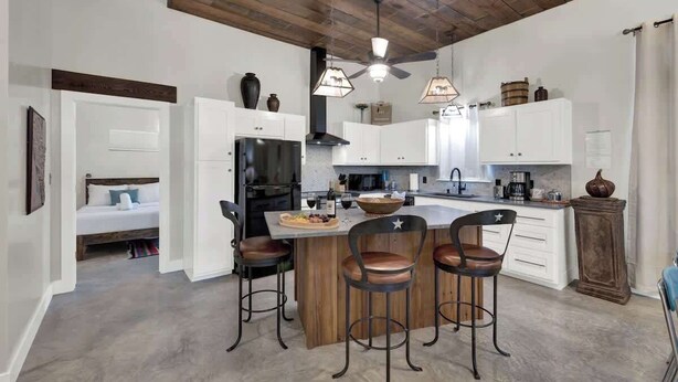 Cozinha moderna com ilha central, banquetas e iluminação pendente.