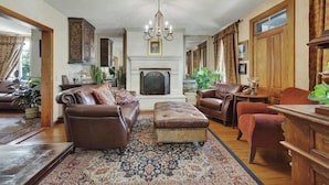 A traditional living room with a fireplace, leather furniture, and a patterned rug.