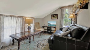 A living room with a sofa, a table, a TV, and a decorative wall piece.