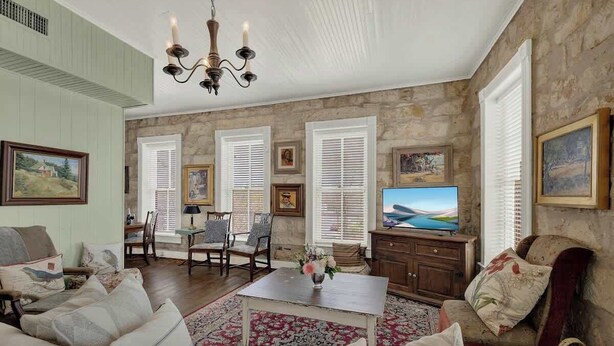 A spacious living room with a fireplace, comfortable seating, a television, and artwork on the walls. - Fountain Suite-stay Right on Historic Main Street in the Heart of Fredericksburg (Fredericksburg)