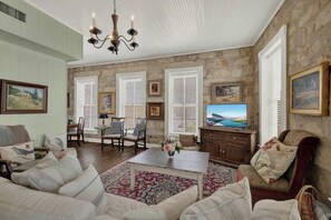 A spacious living room with a fireplace, comfortable seating, a television, and artwork on the walls.