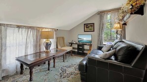 A living room with a sofa, a table, a TV, and a decorative wall piece.