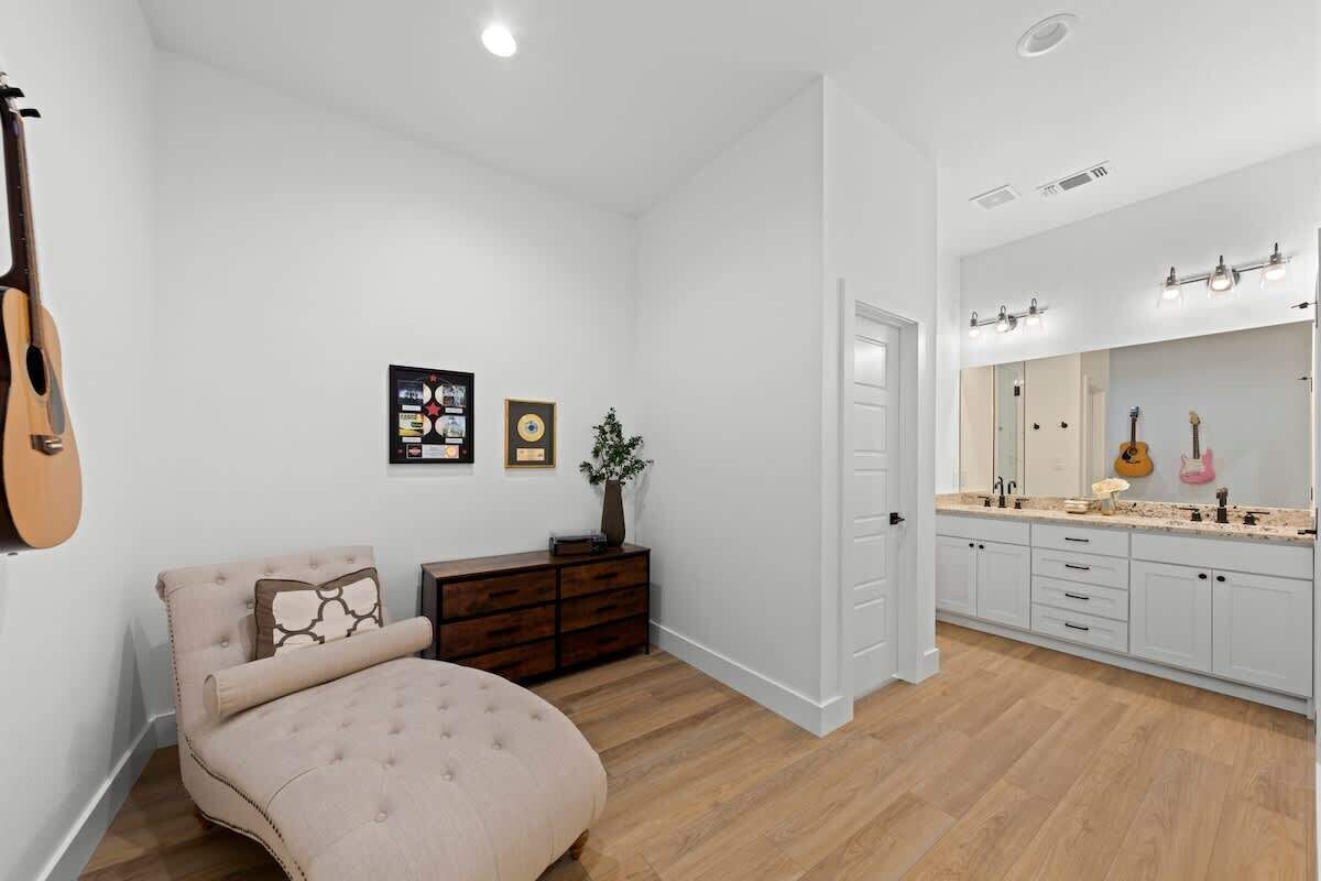 Un dormitorio con cama, cómoda y una guitarra apoyada en la pared.