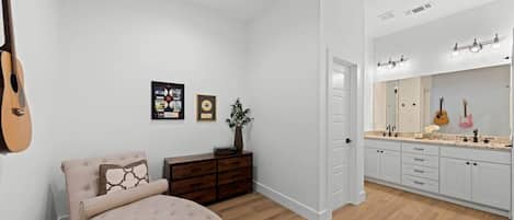 Un dormitorio con cama, cómoda y una guitarra apoyada en la pared.
